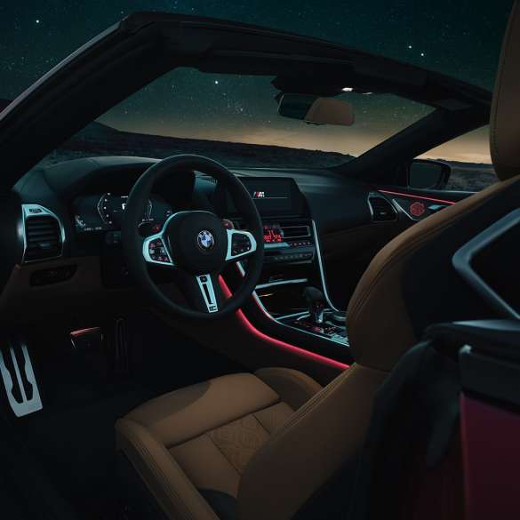 BMW M8 Competition Cabrio, κόκπιτ. BMW M8 Competition Cabrio, κόκπιτ τη νύχτα με δερμάτινο τιμόνι M και κόκκινο ατμοσφαιρικό φωτισμό.