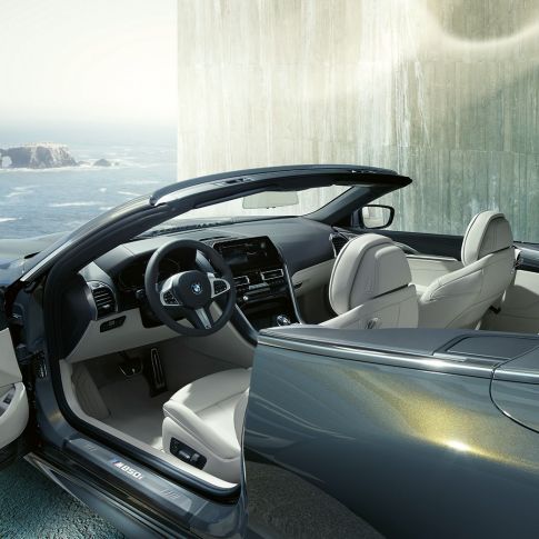 BMW M850i xDrive Cabrio, εσωτερικό. BMW M850i xDrive Cabrio σε γκρι Dravit μεταλλικό με ανοικτή υφασμάτινη οροφή, εσωτερικό με δερμάτινο τιμόνι Μ και επενδύσεις καθισμάτων BMW Individual από δέρμα 'Merino' σε λευκό Ivory.
