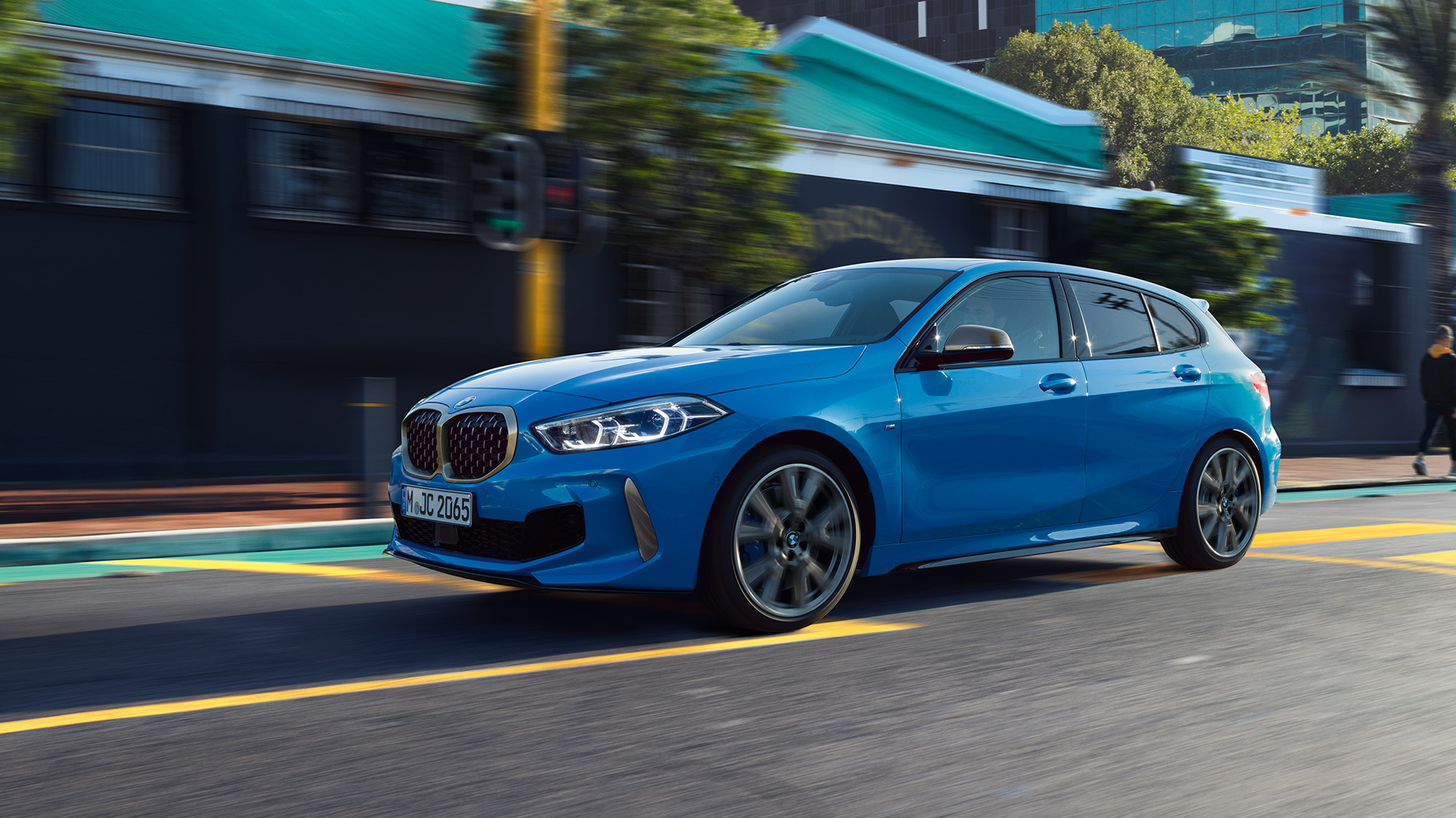 BMW 1 Series, three-quarter side view. BMW 1 Series in Misano Blue metallic, three-quarter front view driving.