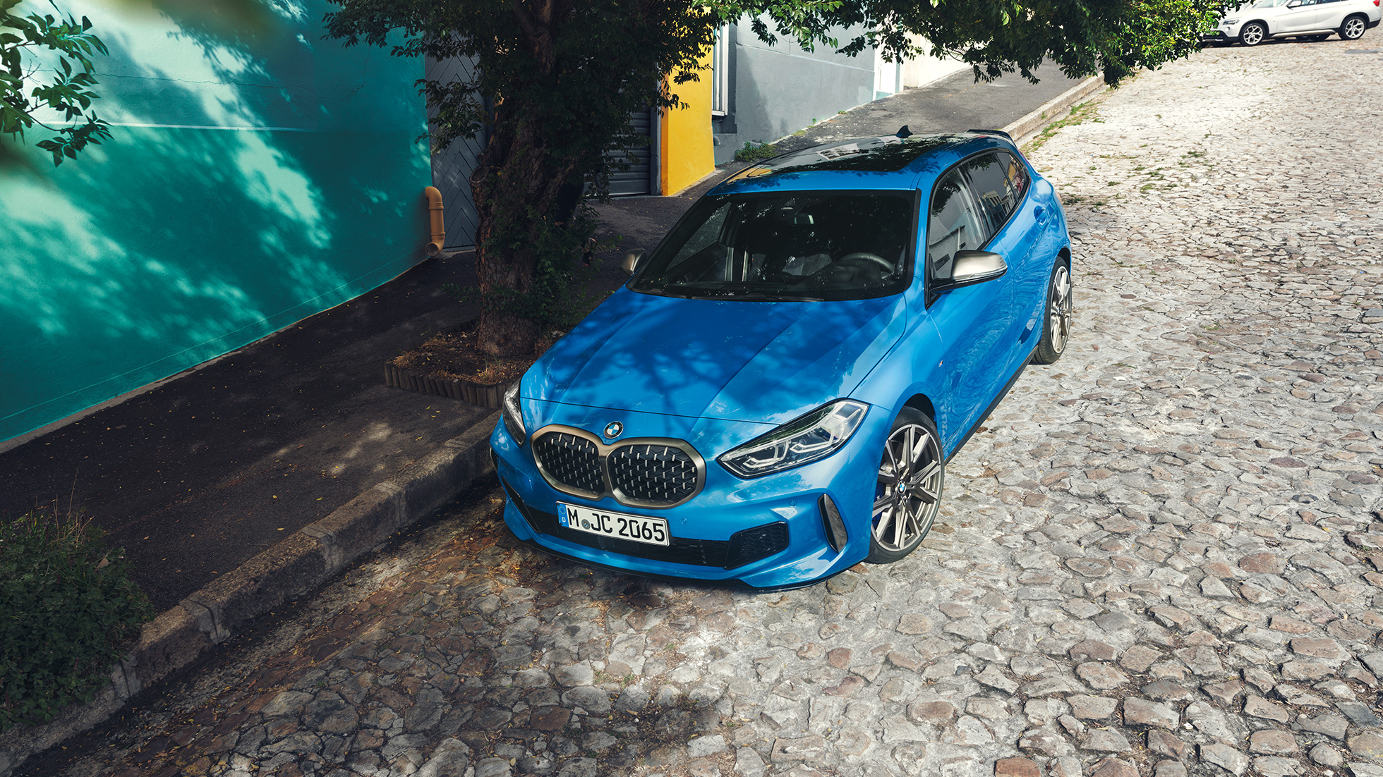 BMW Σειρά 1 στην άκρη του δρόμου. BMW Σειρά 1 σε μπλε Misano μεταλλικό, μπροστινή λήψη τριών τετάρτων, σταθμευμένη στην άκρη του δρόμου, ευρυγώνια λήψη.