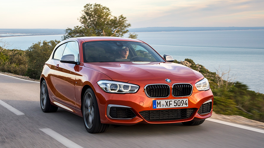 BMW M135i (F21), μπροστινή λήψη τριών τετάρτων, κινούμενη μπροστά από λίμνη και βουνά BMW M135i (F21), μπροστινή λήψη τριών τετάρτων, κινούμενη μπροστά από λίμνη και βουνά