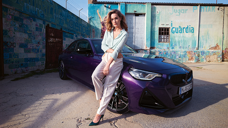 Γυναίκα στηρίζεται στην BMW Σειρά 2 Coupé, G42 2024, μπροστινή λήψη τριών τετάρτων Γυναίκα στηρίζεται στην BMW Σειρά 2 Coupé, G42 2024, μπροστινή λήψη τριών τετάρτων