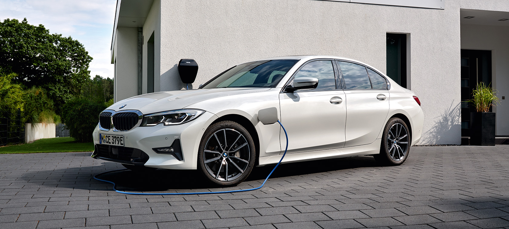 Plug-in υβριδική BMW Σειρά 3 Sedan, 2021 G20, G20, πλαϊνή λήψη τριών τετάρτων, σε φόρτιση Plug-in υβριδική BMW Σειρά 3 Sedan, 2021 G20, πλαϊνή λήψη τριών τετάρτων μπροστά από γκαράζ