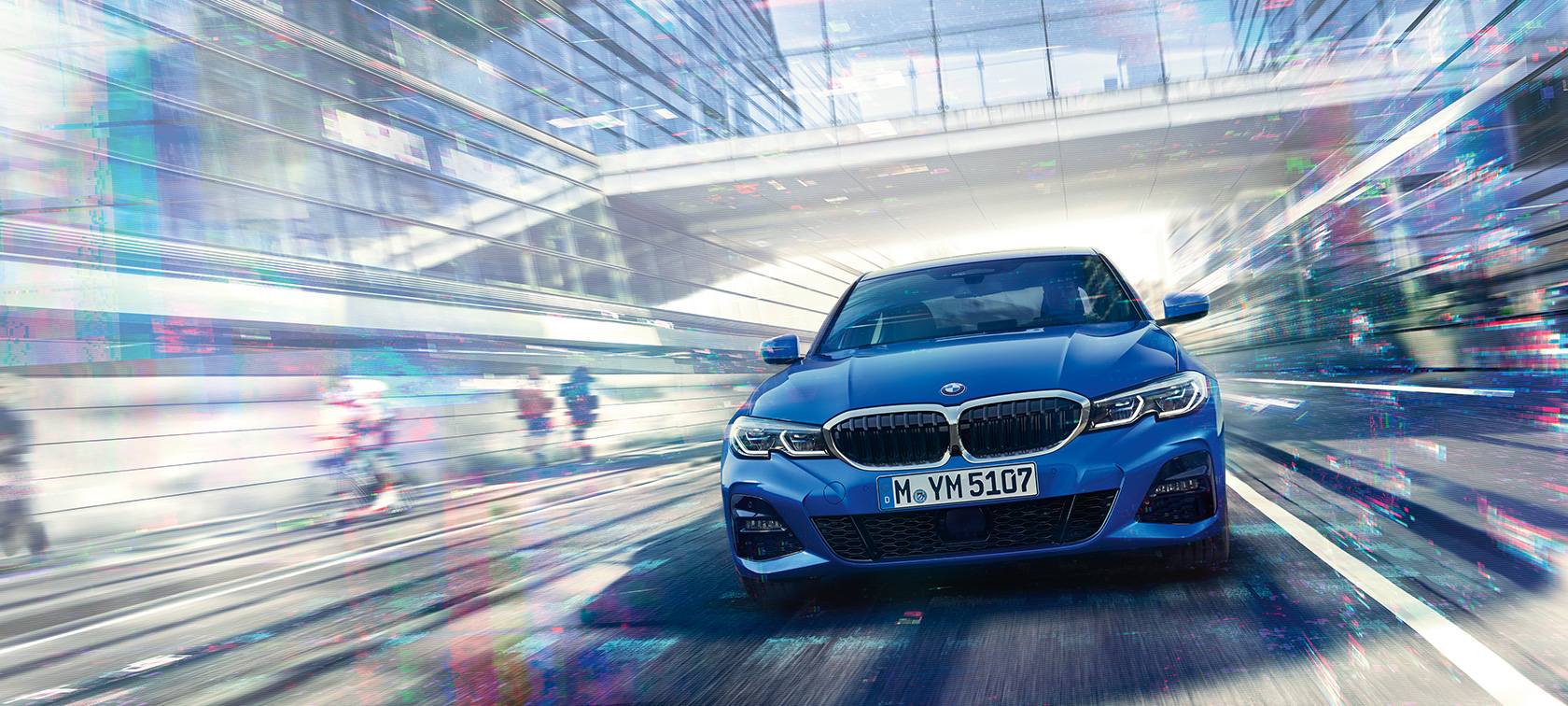 BMW Σειρά 3 Sedan, μπροστινή όψη Μπροστινή όψη της BMW Σειράς 3 Sedan σε κίνηση, την ημέρα, κάτω από γυάλινο κτίριο.