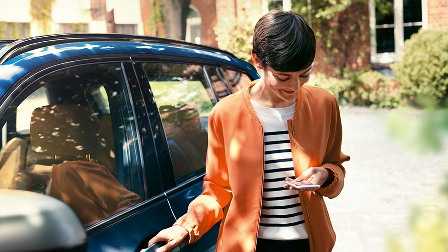 BMW Service, γυναίκα με smartphone δίπλα από την πόρτα μίας BMW BMW Service, γυναίκα με smartphone δίπλα από την πόρτα μίας BMW