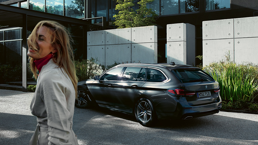 Γυναίκες, BMW Σειρά 5 Touring, G31, Facelift 2020, σε γκρι Sophisto μεταλλικό με εφέ Brilliant, πλαϊνή λήψη 7/8 Γυναίκα μπροστά από σταθμευμένη BMW Σειρά 5 Touring, G31, Facelift 2020, σε γκρι Sophisto μεταλλικό με εφέ Brilliant, πλαϊνή λήψη 7/8