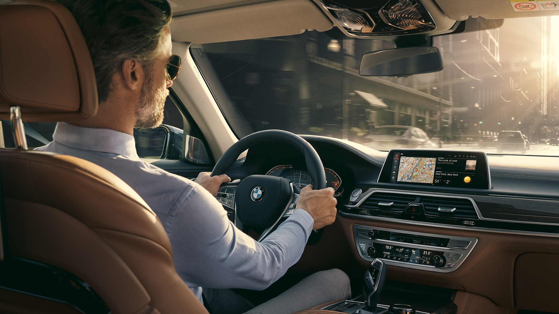 BMW Σειρά 7 Sedan, λειτουργίες συνδεσιμότητας BMW Σειρά 7 Sedan: άντρας κάθεται μέσα στην BMW και χρησιμοποιεί τις λειτουργίες συνδεσιμότητας