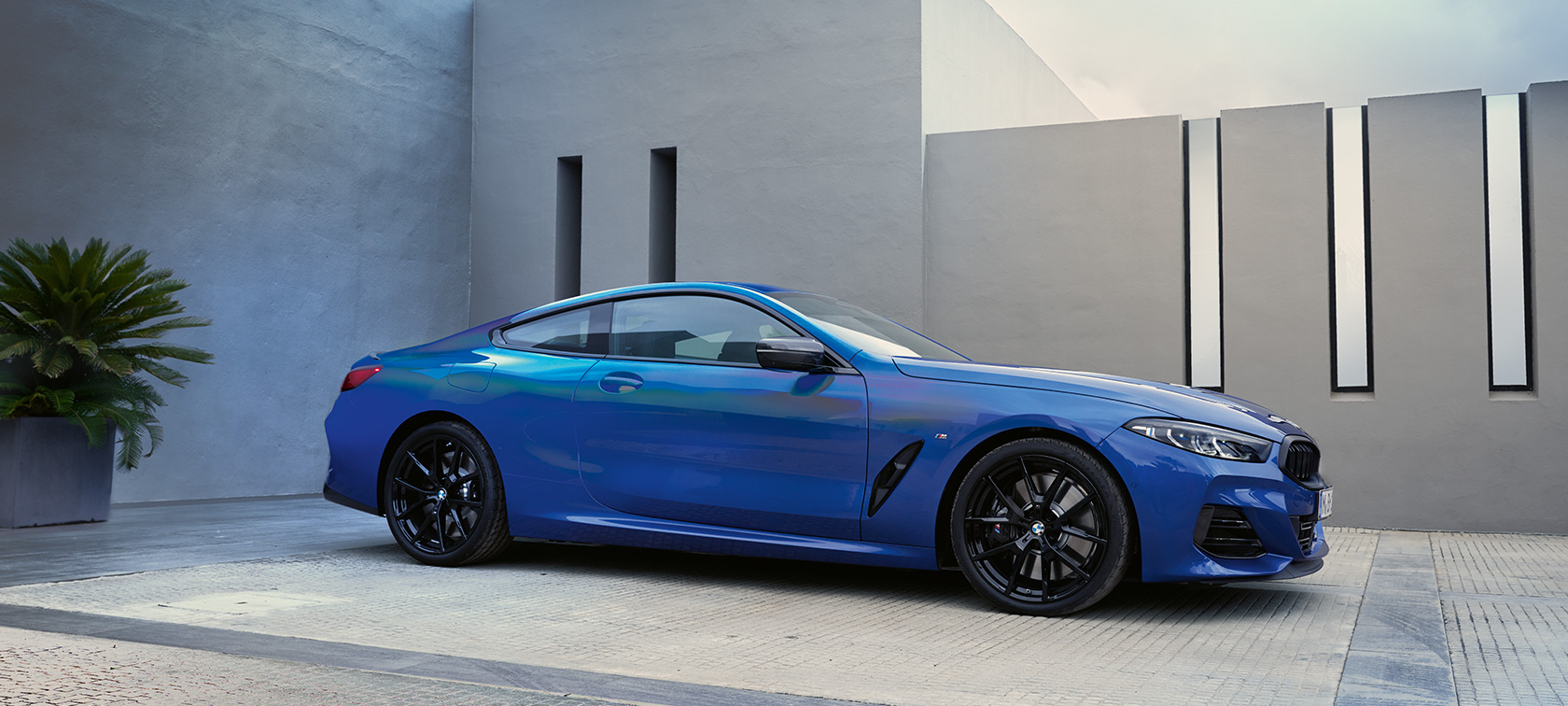 BMW Σειρά 8 Coupé, G15, LCI, Facelift, 2022, M μπλε Portimao μεταλλικό, πλαϊνή λήψη μπροστά από τοίχο σπιτιού