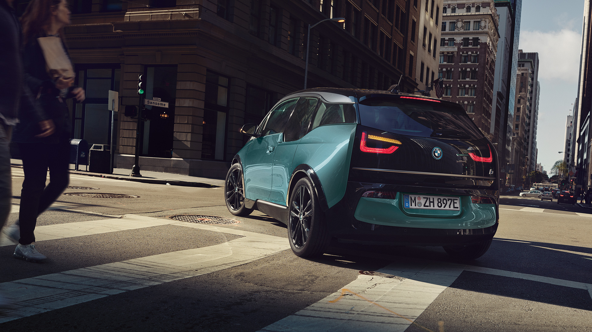 BMW i3 2018, πίσω λήψη τριών τετάρτων, κινούμενο BMW i3 I01 2018, μπεζ Jucaro με διακοσμητικά στοιχεία σε γκρι Frozen μεταλλικό, πίσω λήψη τριών τετάρτων, κινούμενο μπροστά από αστικό σκηνικό