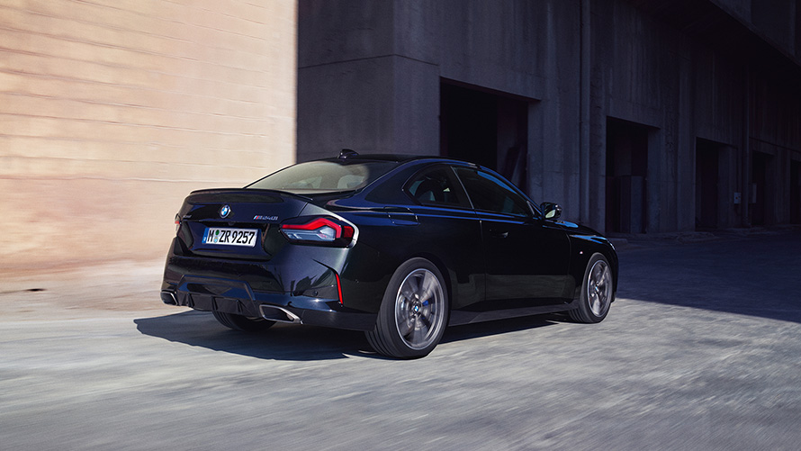 BMW M240i xDrive Coupé, G42, 2021, πίσω λήψη τριών τετάρτων, σταθμευμένη BMW M240i xDrive Coupé, G42, 2021, μαύρο Sapphire μεταλλικό, πίσω λήψη τριών τετάρτων, σταθμευμένη μπροστά από αποθήκη