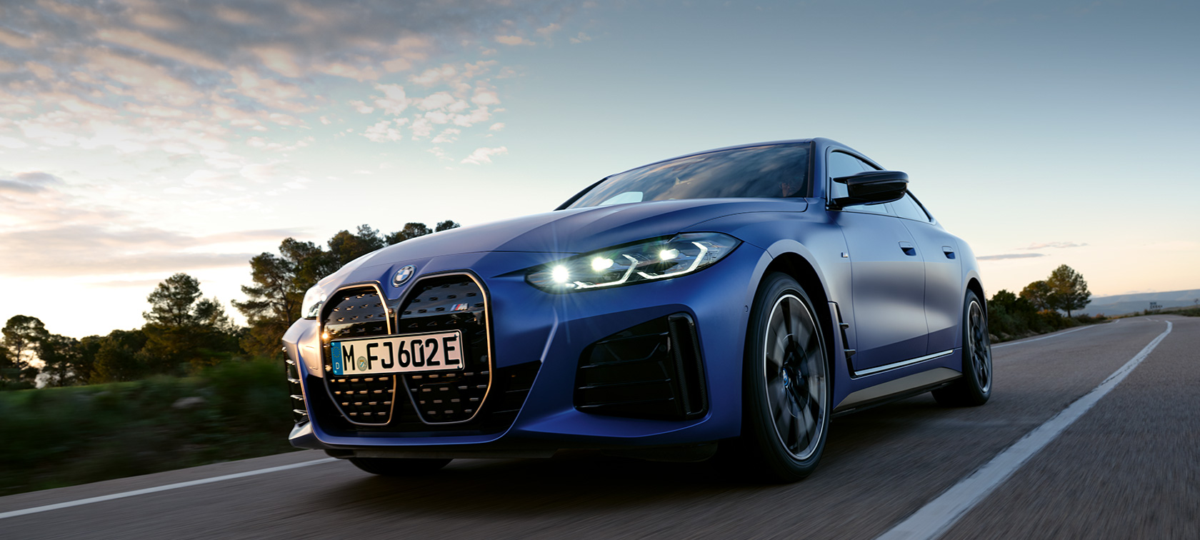 BMW i4 M50, G26, 2021, πλαϊνή λήψη, σταθμευμένη μπροστά από πετρώδες έδαφος BMW i4 M50, G26, 2021, BMW Individual μπλε Frozen Portimao μεταλλικό, πλαϊνή λήψη, σταθμευμένη μπροστά από πετρώδες έδαφος
