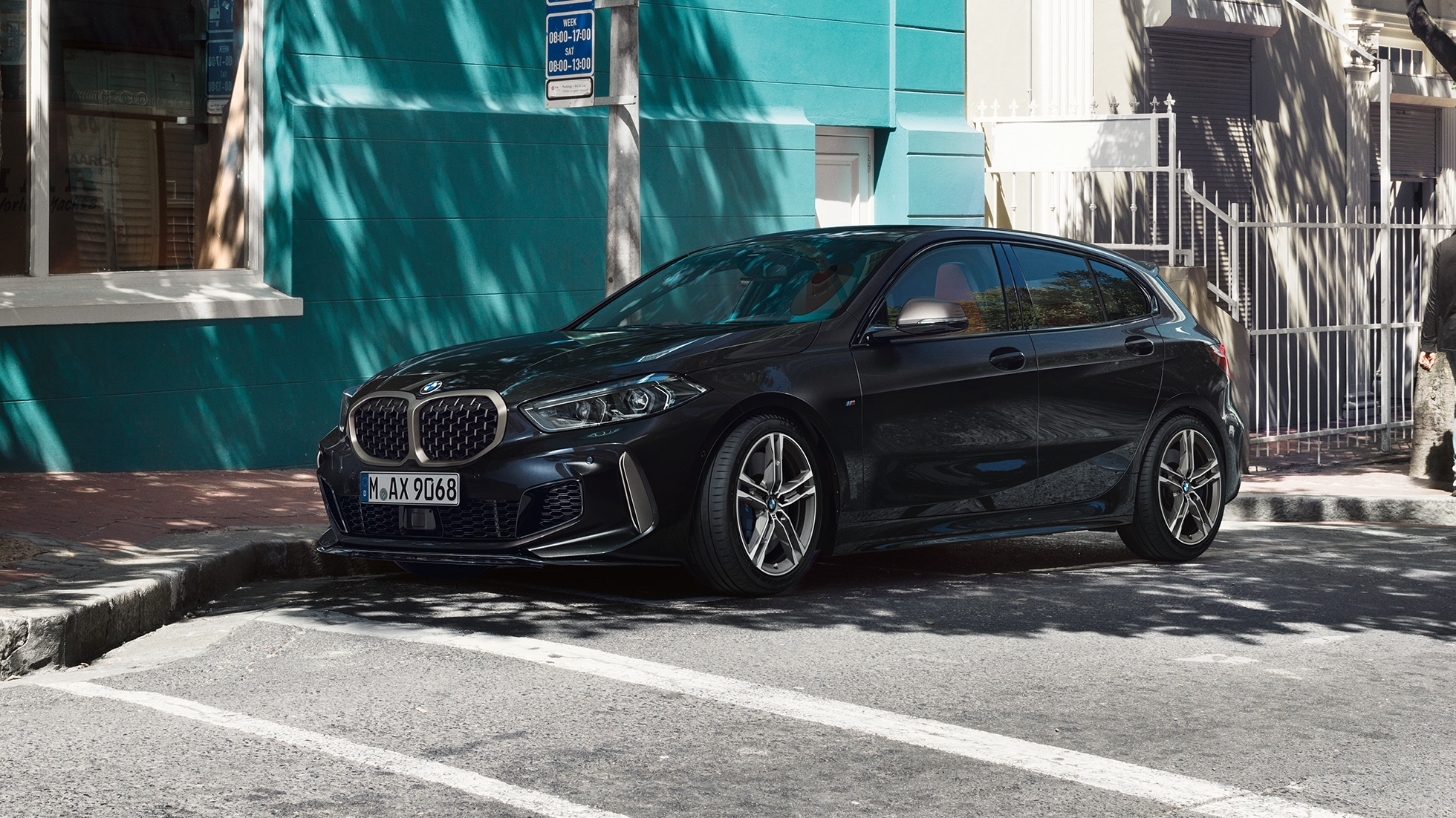 BMW M135i xDrive, πλαϊνή λήψη τριών τετάρτων. Η νέα BMW M135i xDrive σε μαύρο Sapphire μεταλλικό, πλαϊνή λήψη τριών τετάρτων, σταθμευμένη.