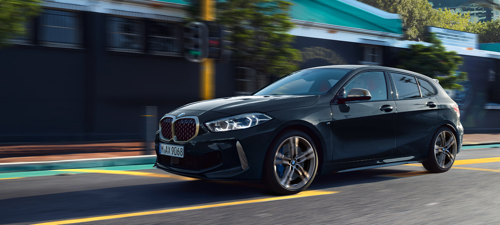 BMW Σειρά 1, M135i xDrive (F40) σε μαύρο Sapphire μεταλλικό, αυτοκίνητο κινούμενο σε αστικό περιβάλλον.