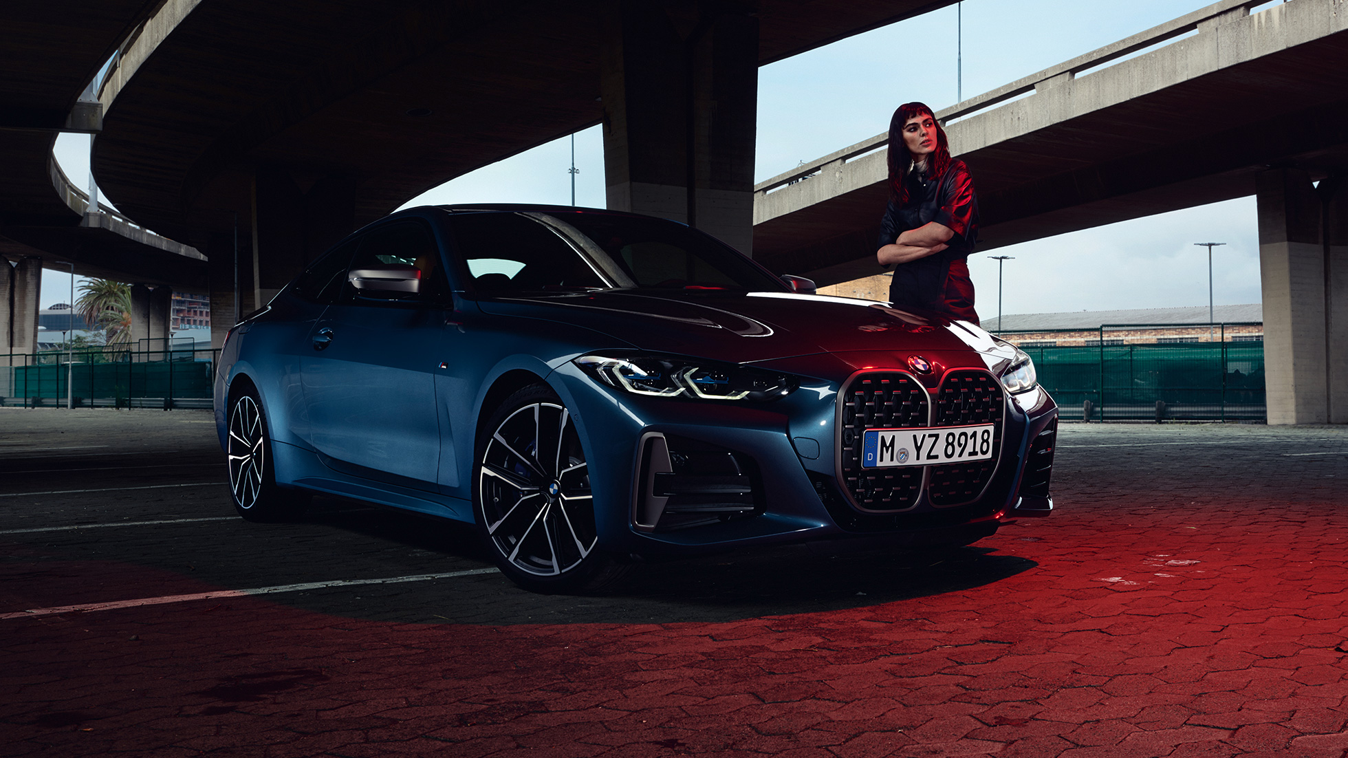 Μοντέλο στέκεται δίπλα από την BMW M440i xDrive Coupé, G22, 2020, πλαϊνή λήψη τριών τετάρτων BMW M440i xDrive Coupé, μπλε Arctic Race μεταλλικό, G22, 2020, πλαϊνή λήψη τριών τετάρτων με μοντέλο