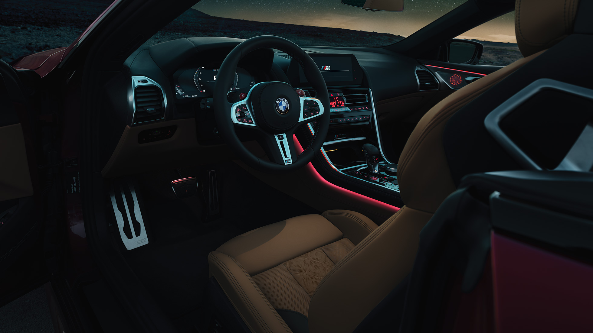 BMW M8 Competition Cabrio, κόκπιτ. BMW M8 Competition Cabrio, κόκπιτ τη νύχτα με δερμάτινο τιμόνι M και κόκκινο ατμοσφαιρικό φωτισμό.