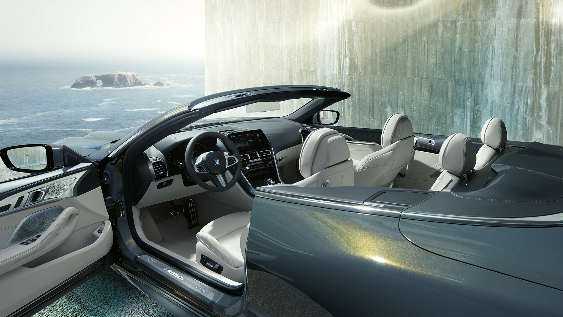 BMW M850i xDrive Cabrio, εσωτερικό. BMW M850i xDrive Cabrio σε γκρι Dravit μεταλλικό με ανοικτή υφασμάτινη οροφή, εσωτερικό με δερμάτινο τιμόνι Μ και επενδύσεις καθισμάτων BMW Individual από δέρμα 'Merino' σε λευκό Ivory.