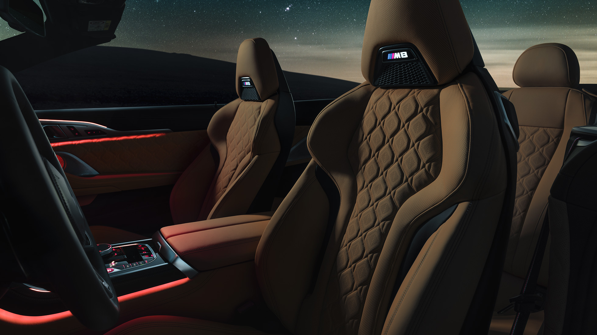 Σπορ καθίσματα M σε δέρμα 'Merino'. BMW M8 Competition Cabrio με ανοικτή υφασμάτινη οροφή κάτω από έναστρο ουρανό, εσωτερικό με σπορ καθίσματα M σε δέρμα 'Merino' και κόκκινο ατμοσφαιρικό φωτισμό.