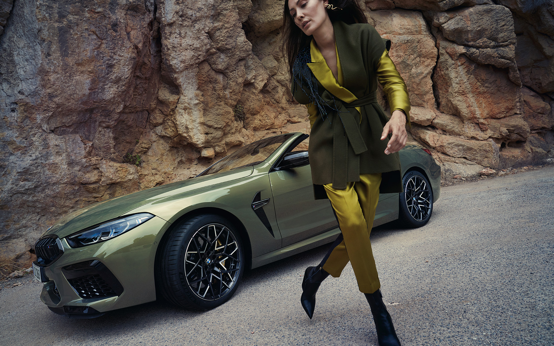 BMW M8 Competition Cabrio, F91, LCI, 2022, μπροστινή λήψη τριών τετάρτων, σταθμευμένη σε πετρώδες έδαφος BMW M8 Competition Cabrio, F91, LCI Facelift, 2022, BMW Individual Brass μεταλλικό, μπροστινή λήψη τριών τετάρτων, σταθμευμένη σε πετρώδες έδαφος με γυναικείο μοντέλο