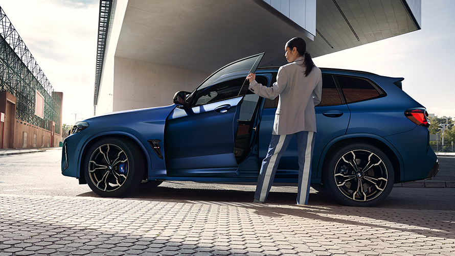 BMW X3 M Competition, F97, LCI, 2021, πλαϊνή λήψη με ανοικτή πόρτα και γυναικείο μοντέλο BMW X3 M Competition, F97, LCI, Facelift, 2021, μπλε Frozen Marina Bay μεταλλικό, πλαϊνή λήψη με ανοικτή πόρτα και γυναικείο μοντέλο