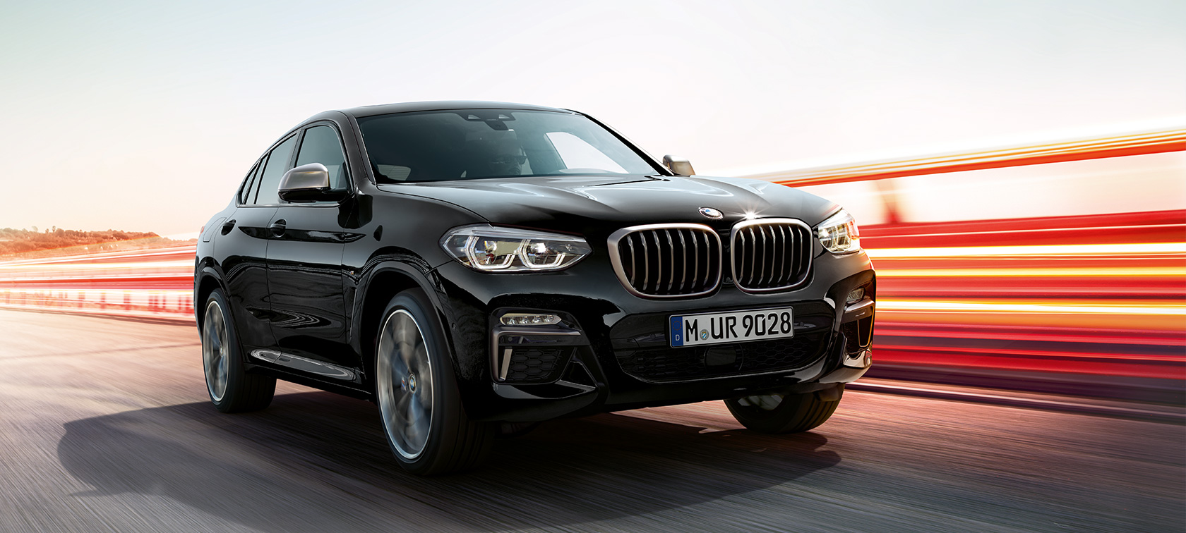 BMW X4 M40i και BMW X4 M40d, μπροστινή λήψη τριών τετάρτων, αριστερή πλευρά. BMW X4 M40i και BMW X4 M40d σε μαύρο Sapphire μεταλλικό, εξωτερικό, μπροστινή λήψη τριών τετάρτων, αριστερή πλευρά, με φωτεινές γραμμές.