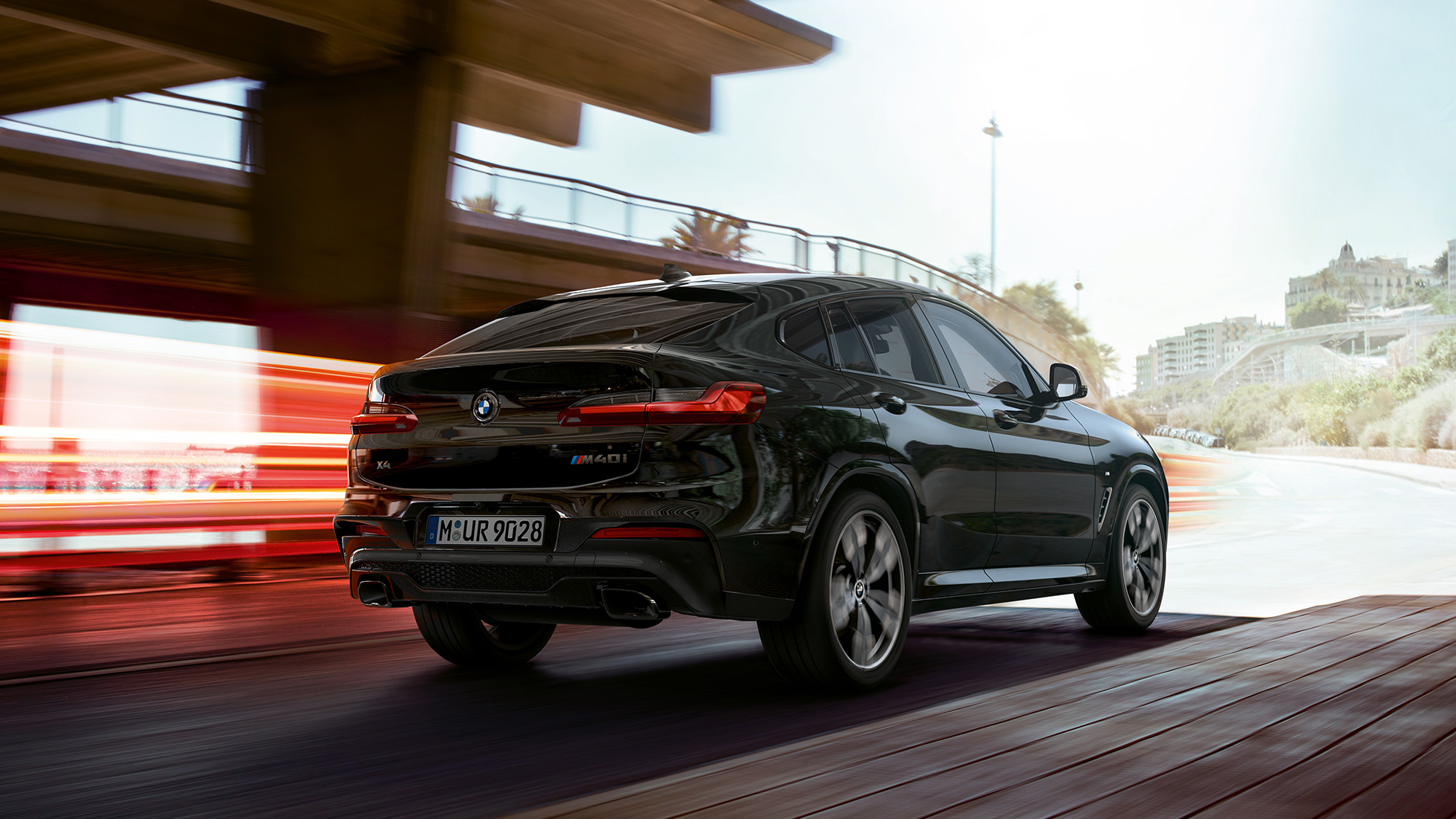 BMW X4 M40i, μπροστινή λήψη τριών τετάρτων. BMW X4 M40i σε μαύρο Sapphire μεταλλικό, σε κίνηση, εξωτερικό, μπροστινή λήψη τριών τετάρτων με φωτεινές γραμμές.