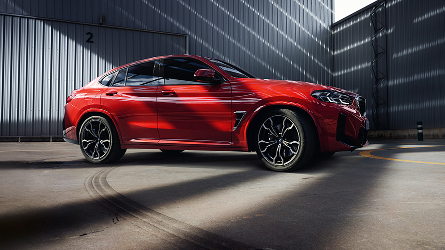 BMW Χ4 Μ, F98, LCI, Facelift, 2021, κόκκινο Toronto μεταλλικό, πλαϊνή λήψη, μπροστά από βιομηχανικό κτίριο
