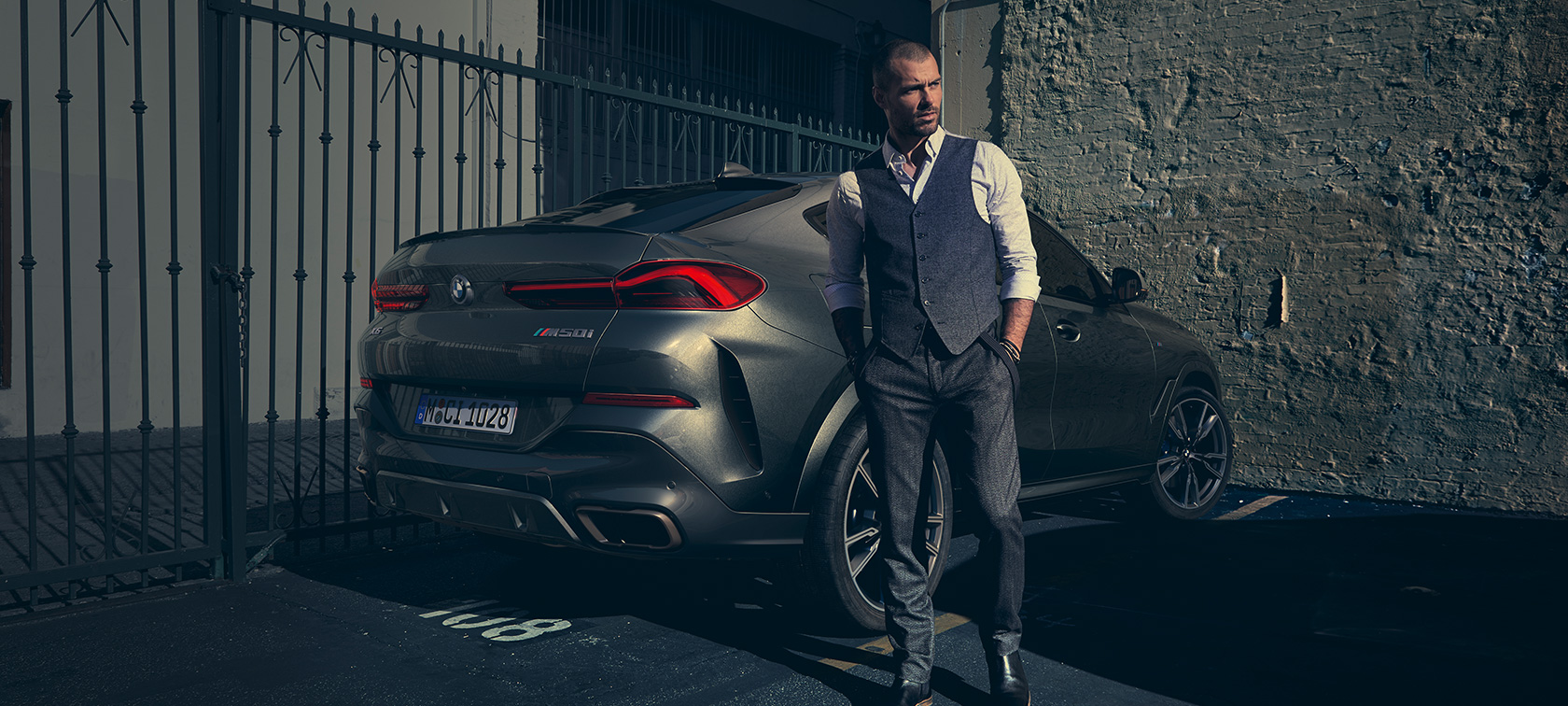 BMW X6 M50i σε πίσω λήψη τρία τέταρτα Άντρας στέκεται δίπλα στην BMW X6 M50i SUV σε πίσω λήψη τρία τέταρτα