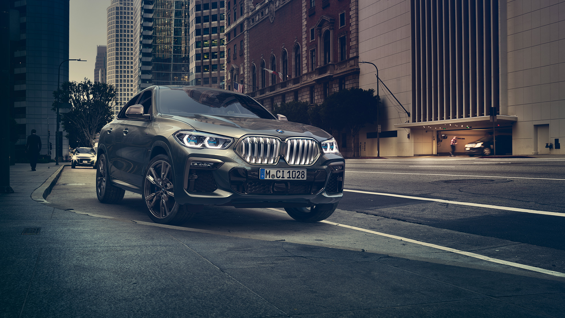 BMW X6 M50i στατική BMW X6 M50i σε μπροστινή λήψη τρία τέταρτα στατική σε αστικό σκηνικό.