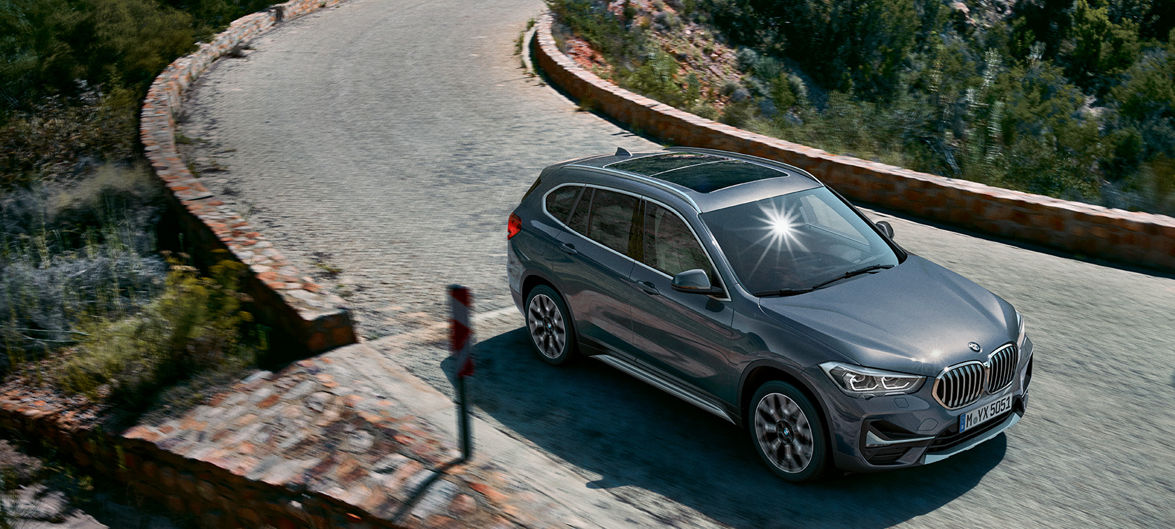 BMW X1, μπροστινή λήψη τριών τετάρτων. BMW X1, μπροστινή λήψη τριών τετάρτων, σε κίνηση, μπροστά από ορεινό τοπίο.