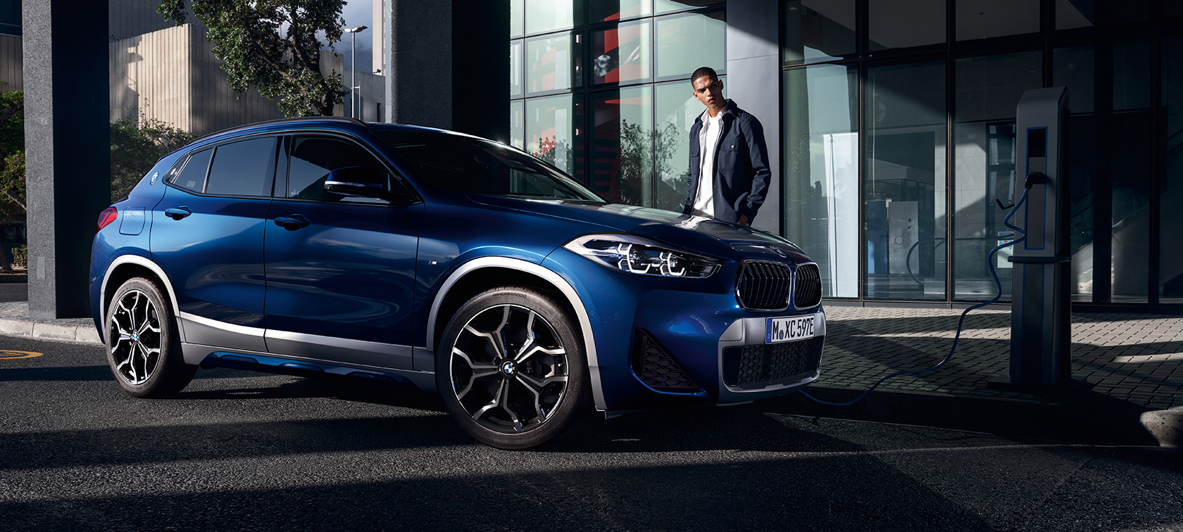 BMW X2 xDrive25e με τεχνολογία Plug-in Hybrid, F39, πλαϊνή λήψη τριών τετάρτων σε σταθμό φόρτισης BMW X2 xDrive25e με τεχνολογία Plug-in Hybrid, F39, πλαϊνή λήψη τριών τετάρτων σε σταθμό φόρτισης με μοντέλο