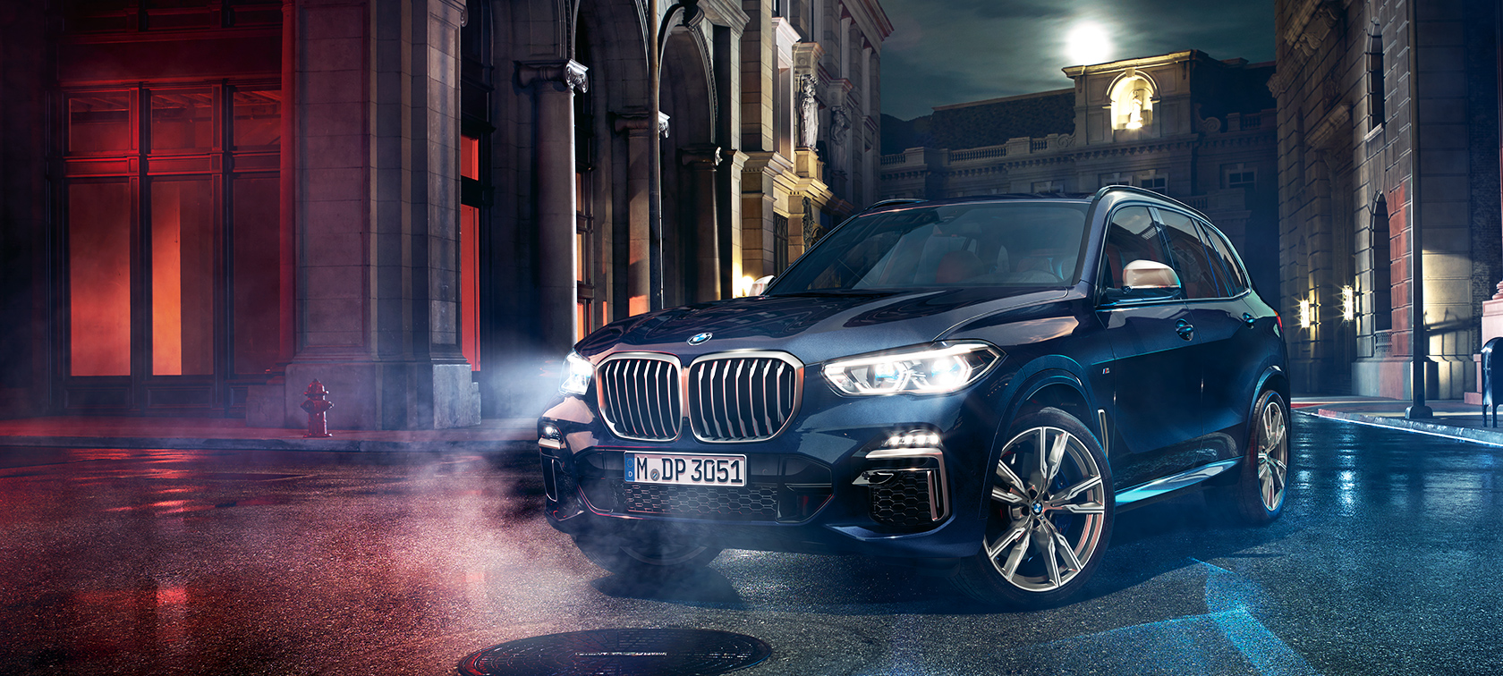 BMW X5 M50d στον δρόμο Η BMW X5 M M50d στέκεται στον δρόμο, μπροστά από ένα νυχτερινό σκηνικό πόλης