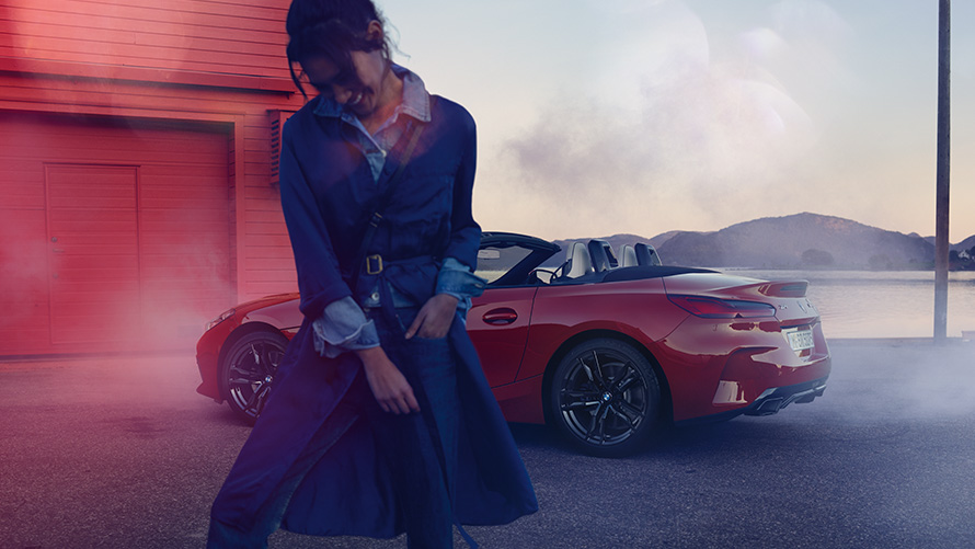 BMW Z4 M40i Roadster, G29, με ανοικτή υφασμάτινη οροφή BMW Z4 M40i Roadster, G29, πίσω λήψη τριών τετάρτων με ανοικτή υφασμάτινη οροφή και γυναίκα στο προσκήνιο