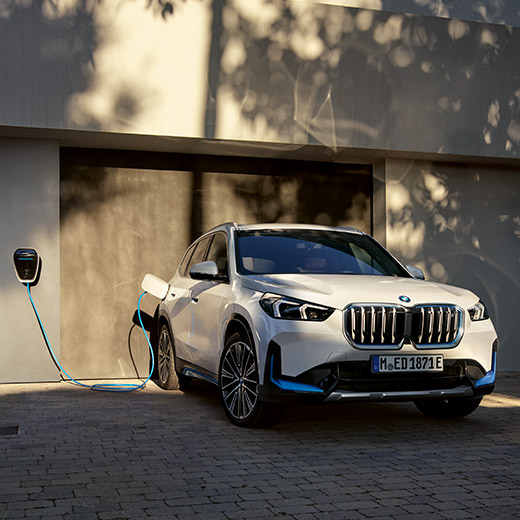 BMW iX1 U11, BEV, σε φόρτιση μπροστά από γκαράζ