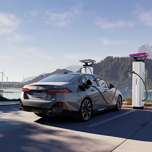 BMW i5 eDrive40, G60, σε σταθμό φόρτισης μπροστά από λίμνη