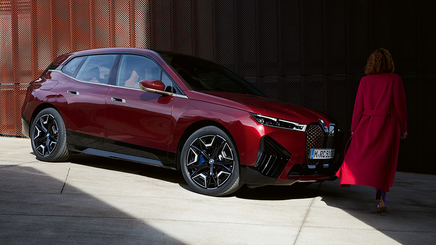 BMW Ψηφιακό Κλειδί Plus, BMW iX μπροστινή λήψη τριών τετάρτων με γυναίκα με κόκκινο παλτό BMW Ψηφιακό Κλειδί Plus, BMW iX μπροστινή λήψη τριών τετάρτων με γυναίκα με κόκκινο παλτό