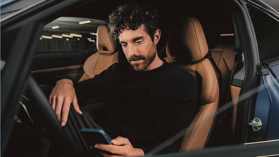 Άντρας κάθεται σε μία BMW Άντρας κάθεται σε μία BMW και κοιτά το smartphone