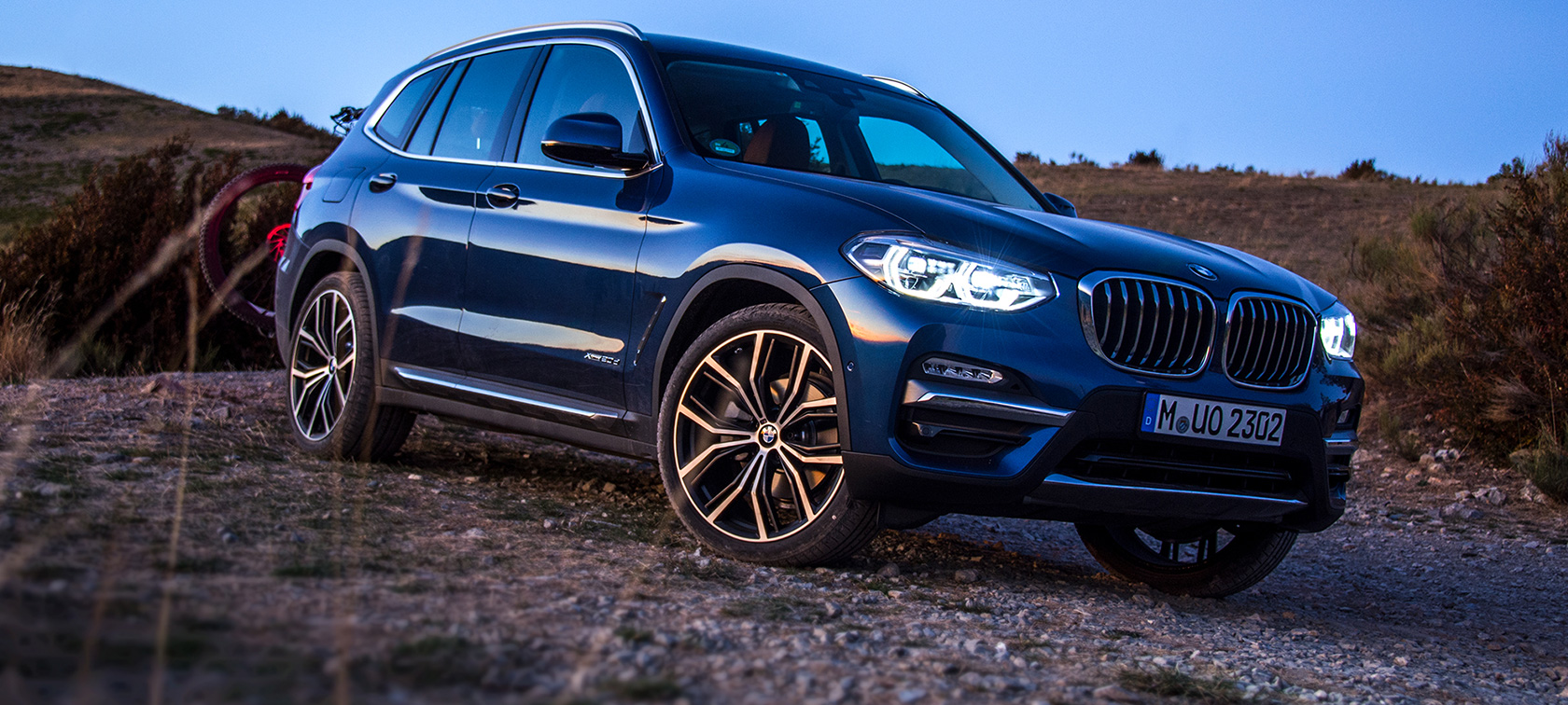 Μπλε BMW X3 σε ανοικτό χώρο Σταθμευμένη μπλε BMW X3 με βάση μεταφοράς και ποδήλατο σε ανοικτό χώρο