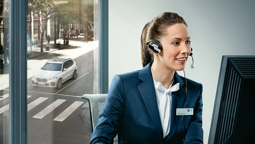 Concierge Services Concierge Services: υπάλληλος της BMW κάθεται στο γραφείο της φορώντας ακουστικά