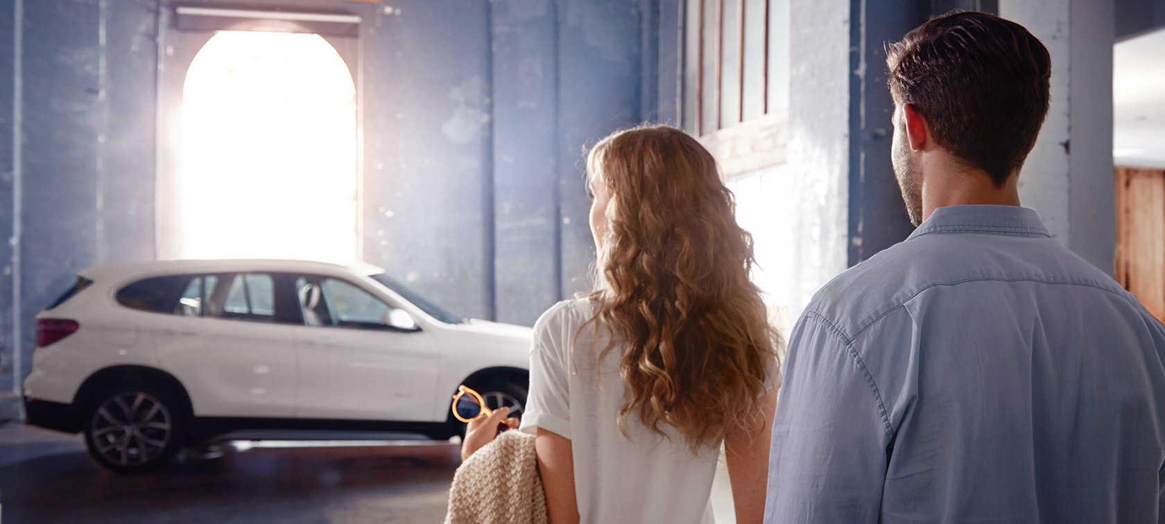 Ζευγάρι μπροστά από μία BMW σε κτίριο BMW Financial Services, ζευγάρι μπροστά από μία BMW σε κτίριο