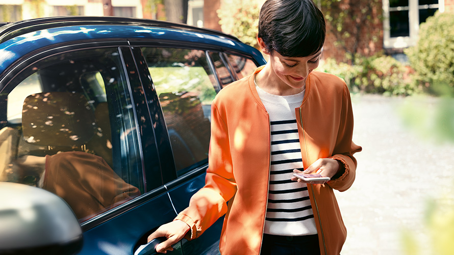 BMW Teleservice Γυναίκα με smartphone στέκεται στην πόρτα της BMW