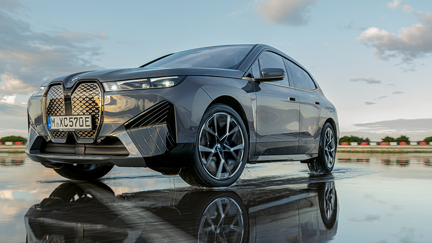 BMW Τροχοί, μπροστινή λήψη τριών τετάρτων της BMW iX (i20), κινούμενη σε βρεγμένο δρόμο BMW Τροχοί, μπροστινή λήψη τριών τετάρτων της BMW iX (i20), κινούμενη σε βρεγμένο δρόμο