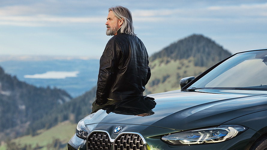 Άντρας στηρίζεται επάνω σε μία BMW, μπροστά σε ορεινό τοπίο BMW Αξεσουάρ για την Άνοιξη και το Καλοκαίρι, άντρας στηρίζεται επάνω σε μία BMW, μπροστά σε ορεινό τοπίο