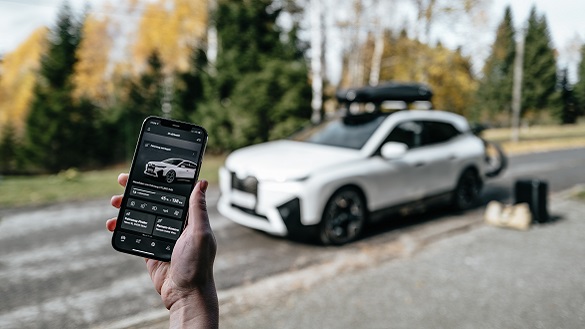 Οθόνη κινητού τηλεφώνου με την My BMW App, στο παρασκήνιο μια BMW iX Οθόνη κινητού τηλεφώνου με την My BMW App, στο παρασκήνιο μια BMW iX
