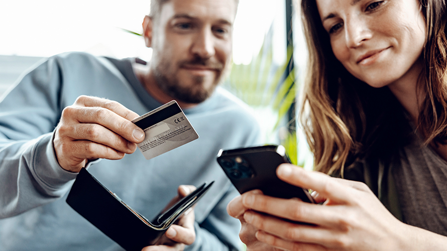 Άντρας και γυναίκα κοιτούν το smartphone. Ο άντρας κρατά μια πιστωτική κάρτα. Άντρας και γυναίκα κοιτούν το smartphone. Ο άντρας κρατά μια πιστωτική κάρτα.