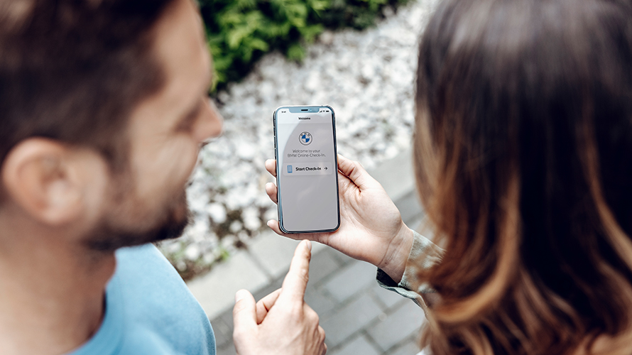Άντρας δείχνει προς την οθόνη του smartphone. Στην οθόνη προβάλλεται το λογότυπο BMW. Άντρας δείχνει προς την οθόνη του smartphone. Στην οθόνη προβάλλεται το λογότυπο BMW.