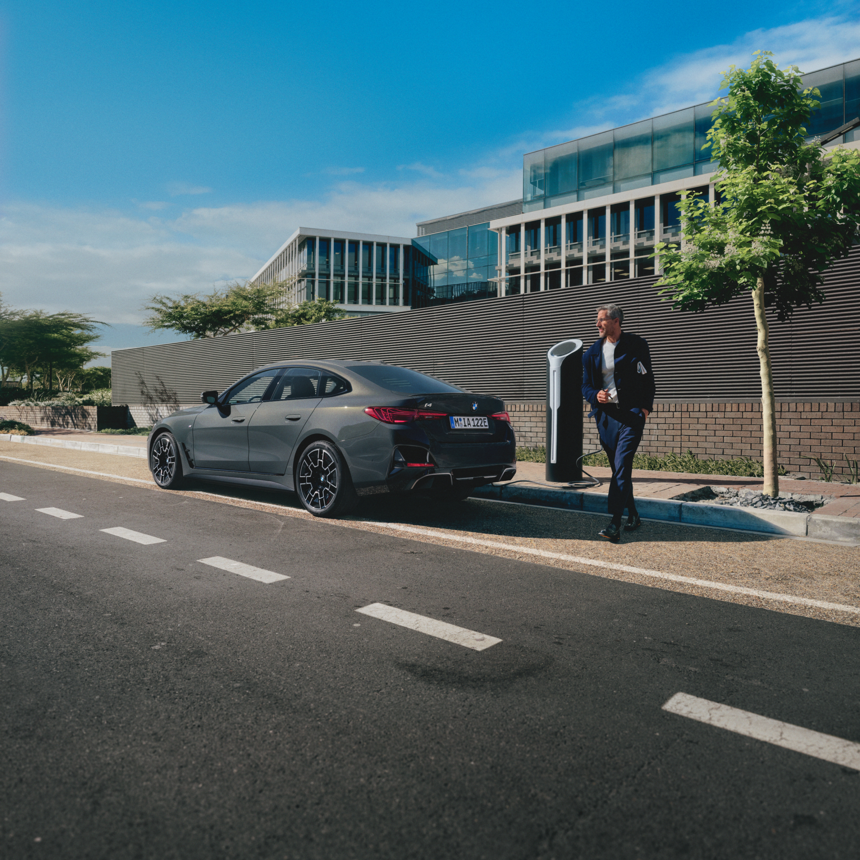 Ένας άνθρωπος στέκεται πίσω από μια BMW που φορτίζει στην άκρη του δρόμου