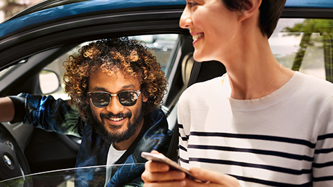 BMW Financial Services, άντρας κάθεται μέσα σε μία BMW και γυναίκα με smartphone BMW Financial Services, άντρας κάθεται μέσα σε μία BMW και γυναίκα με smartphone